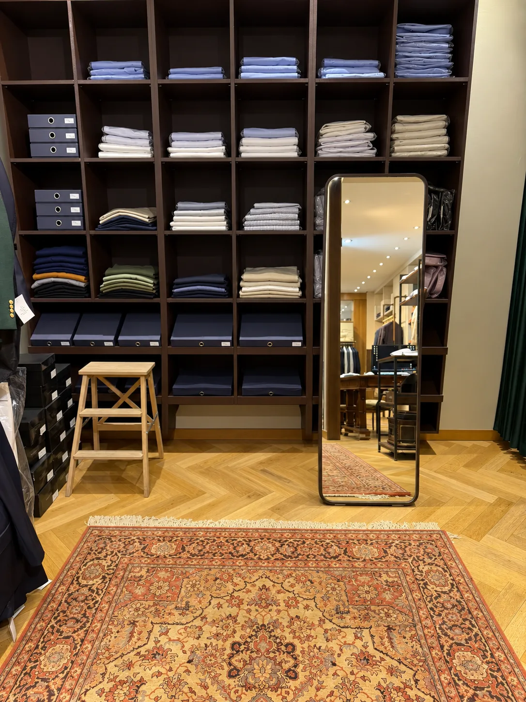 The fitting room at BEGENTLEMEN, with shirt shelving and a standing mirror